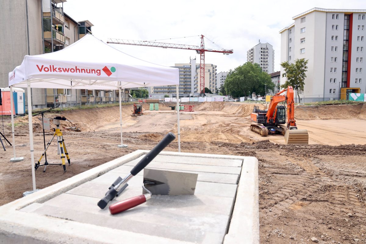 Foto von der Grundsteinlegung des Staudenplatzes. Der Grundstein liegt im Vordergrund und im Hintergrund steht ein Bagger.