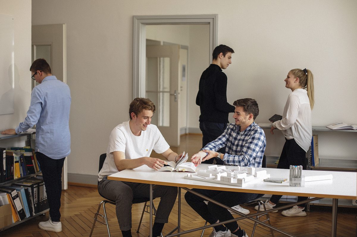 Eine Gruppe von Auszubildenden tauscht sich im Büro aus.