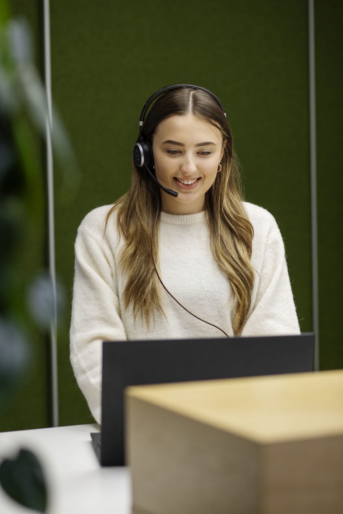 Eine junge Frau mit Headset telefoniert gut gelaunt.