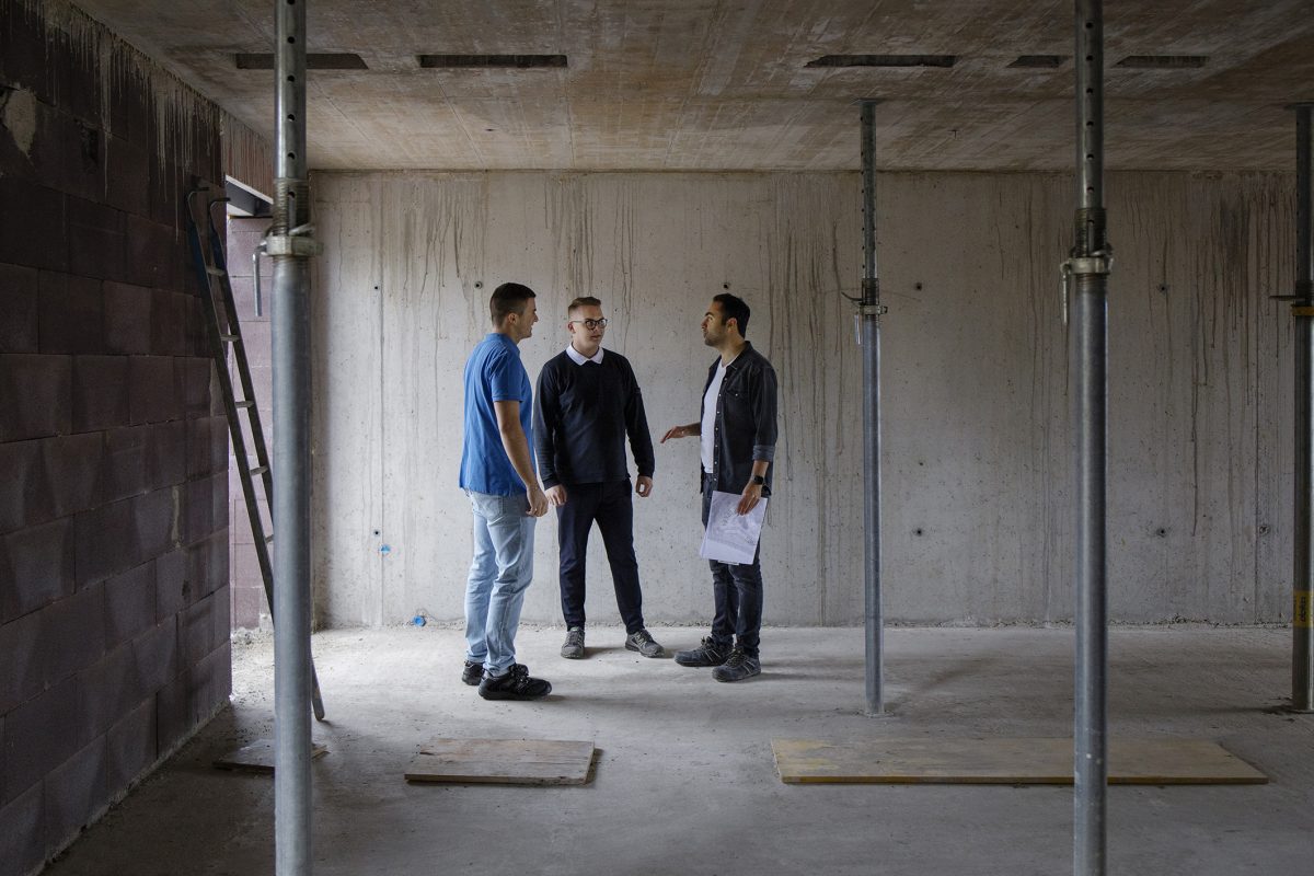 Drei Menschen besprechen sich auf einer Baustelle.