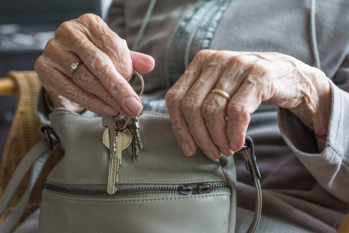 Eine ältere Frau hält ihre Handtasche und den Wohnungsschlüssel in der Hand.