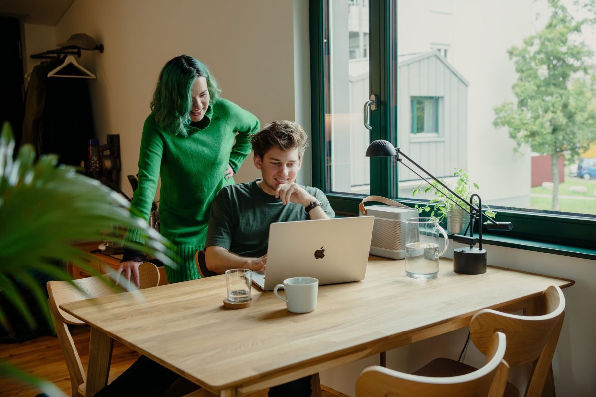 Einblick ins Wohnzimmer des Neubauprojektes Garagenaufstockung in Karlsruhe Rintheim. Ein Mann sitzt am Tisch und arbeitet, eine Freu steht hinter ihm und schaut ihm über die Schulter.