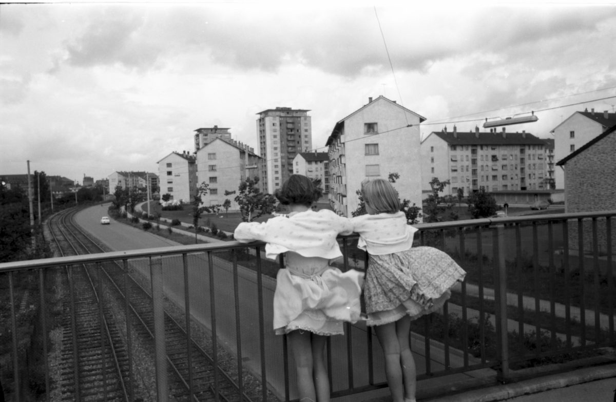 Zwei kleine Mädchen stehen auf einer Brücke und schauen auf die Straßenbahngleise beim Mühlburger Feld herab. Die historische Aufnahme hat Horst Schlesiger etwa 1960 gemacht.