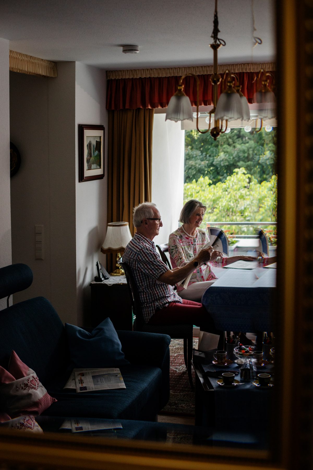 Ein älteres Ehepaar sitzt am Esstisch und liest Zeitung.