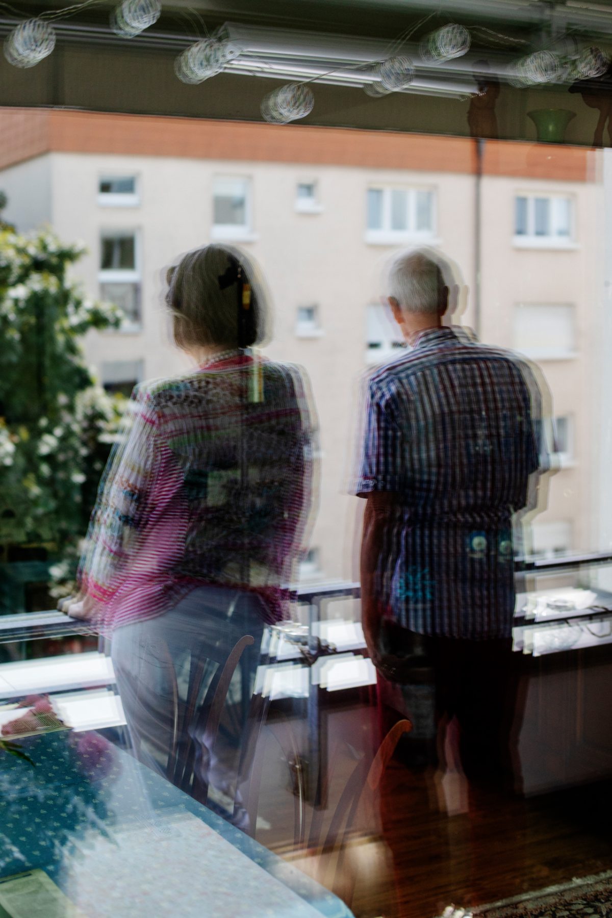 Ein älteres Ehepaar steht auf dem Balkon und blickt in die Ferne.