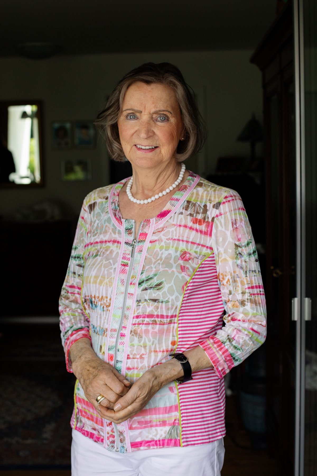 Eine ältere Frau steht in der Balkontüre und blickt freundlich in die Kamera.