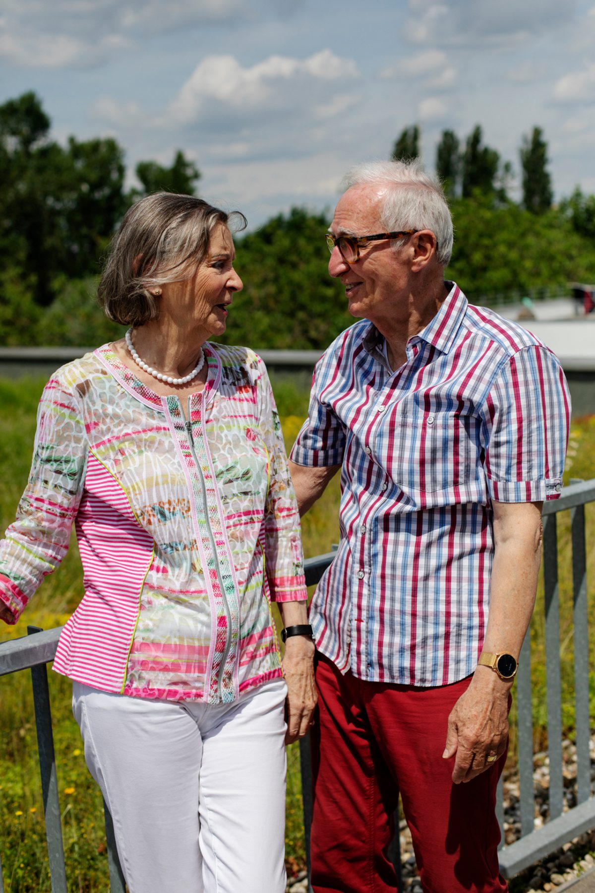 Ein älteres Ehepaar steht an einem Geländer vor einer begrünten Dachfläche und unterhält sich.