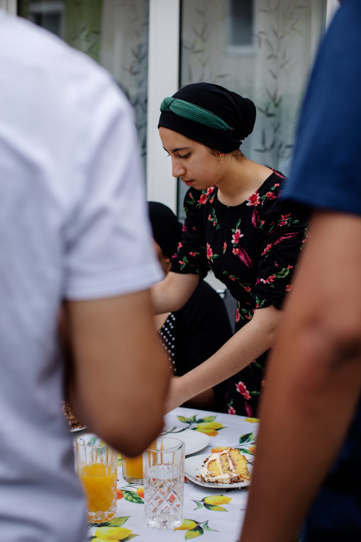 Eine junge Frau mit Kopftuch serviert am Kaffeetisch.