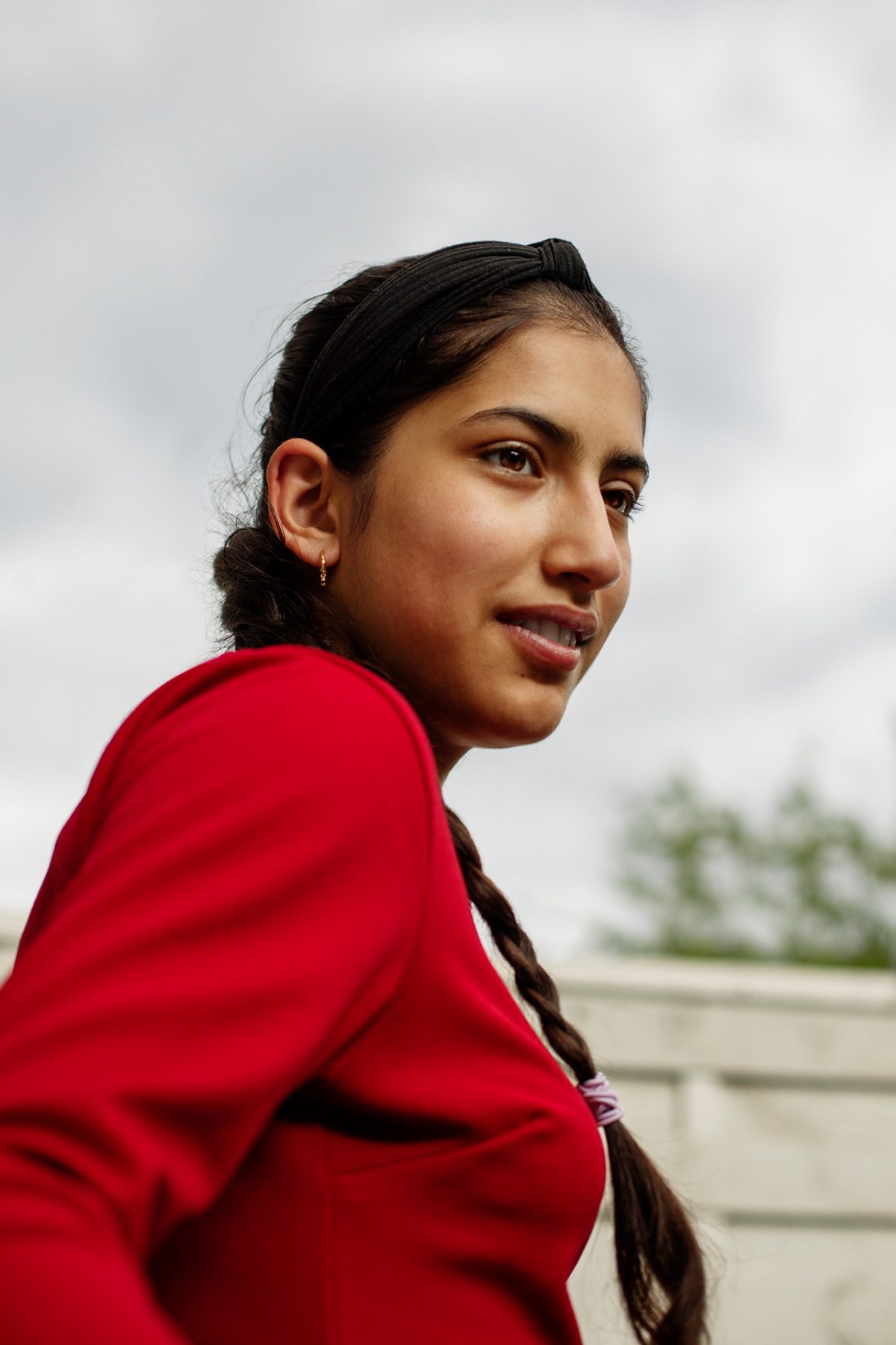 Eine junge Frau lächelt schüchtern an der Kamera vorbei.