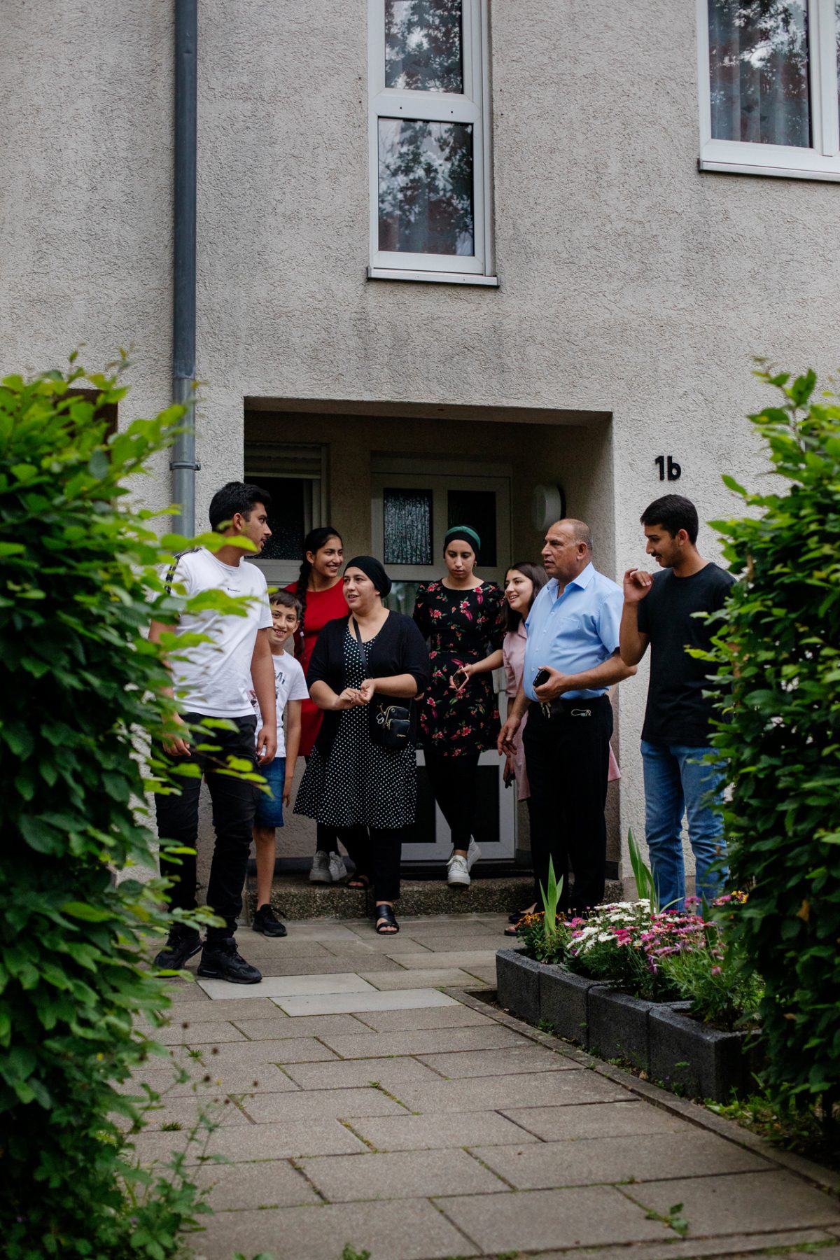 Eine große Familie steht vor dem Hauseingang ihres Mietshauses der Volkswohnung.