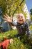 Ein Kleinkind krabbelt auf der Wiese und streckt die Hand aus.