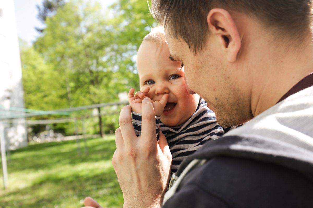 Ein junger Vater hält ein Kleinkind auf dem Arm.