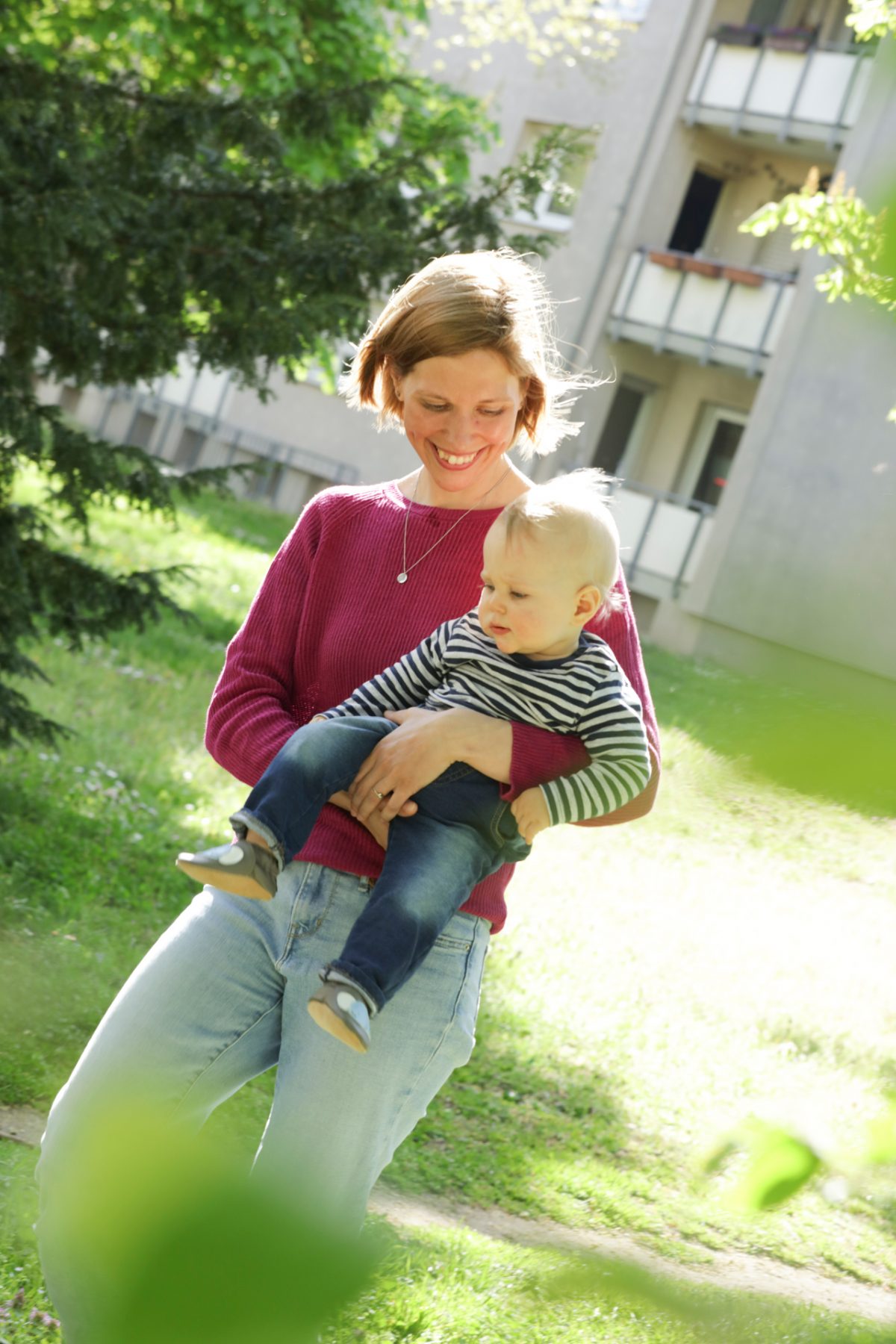 Eine junge Mutter hält glücklich ihr Kleinkind auf dem Arm.