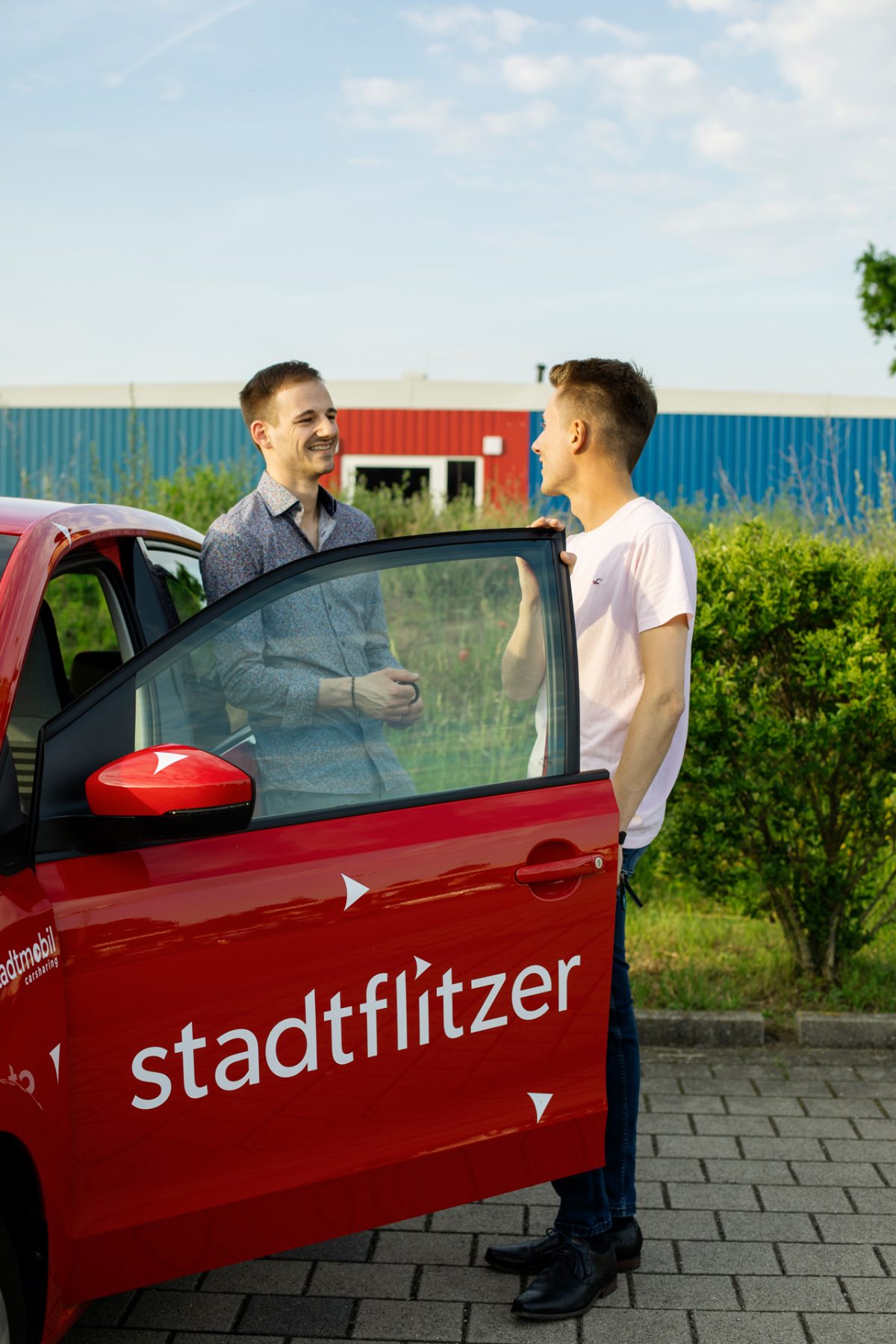 Zwei junge Männer stehen an einem Stadtflitzer von Stadtmobil.
