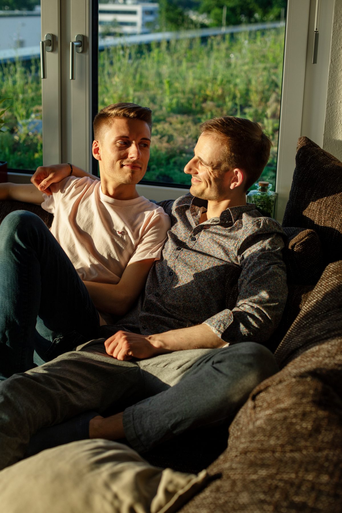 Zwei junge Männer sitzen gemütlich auf ihrer Couch in der Mietwohnung der Volkswohnung.