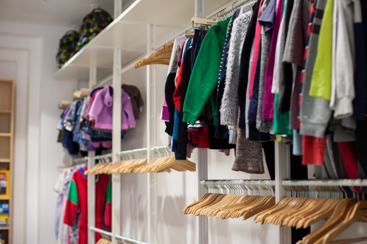 Viele Kleidungsstücke hängen auf Bügeln an Standen, unten sind einige Reihen leere Bügel zu sehen.