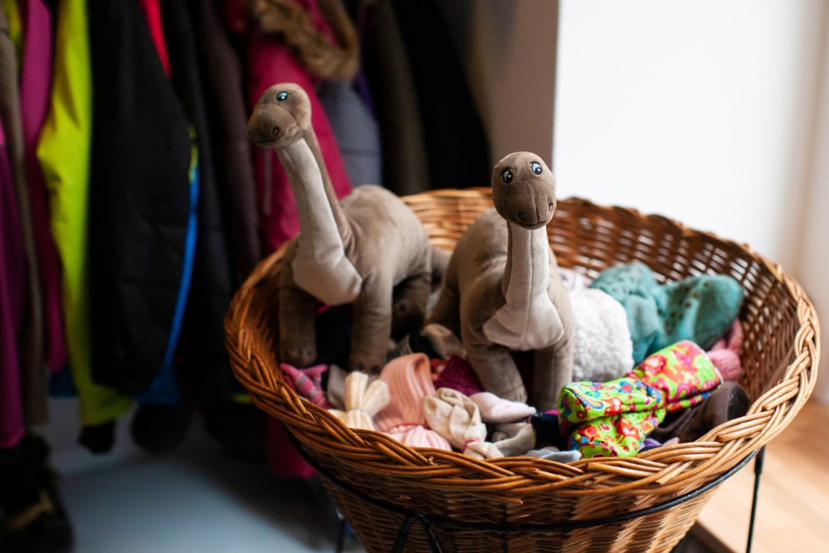 Zwei Dinosaurier aus Plüsch stehen in einem Korb mit Socken.