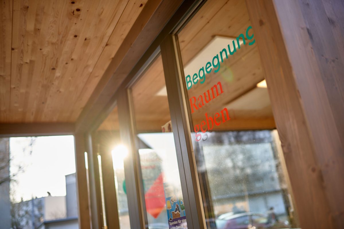 Stimmungsbild des Tiny House in der Nordweststadt mit dem Schriftzug Begegnung Raum geben auf der Glastüre.