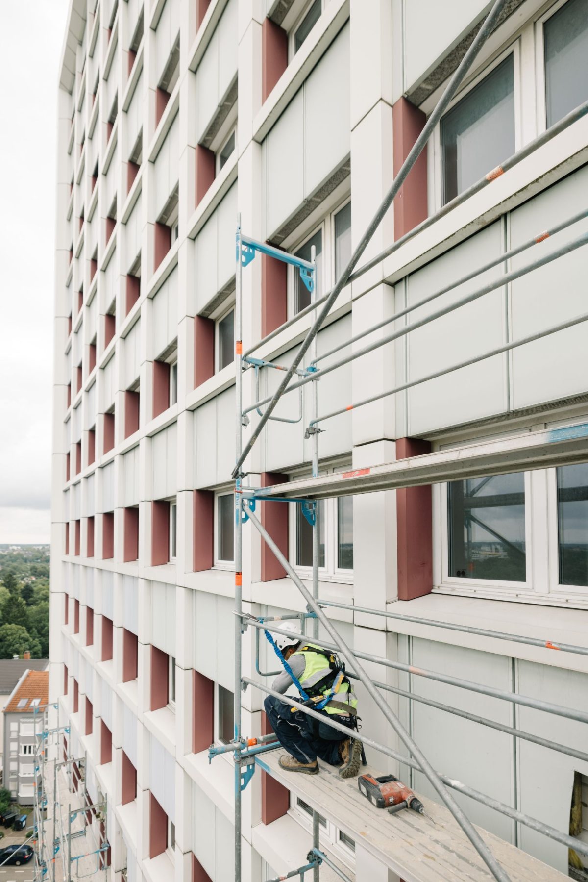 Fassade eines modernisierten Mietshauses in Mühlburg. Ein Handwerker bringt das Gerüst an der Außenwand an.