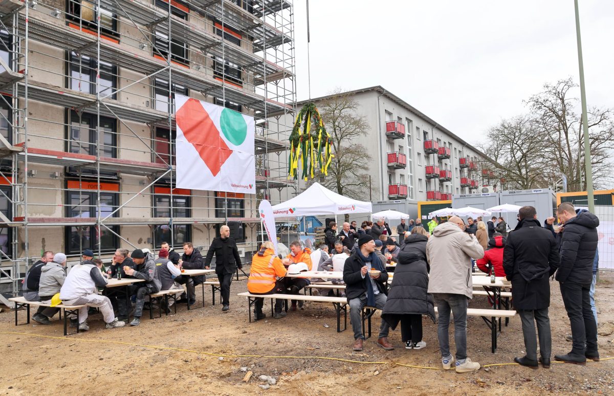 Viele Gäste kamen zum Richtfest auf die Baustelle. Sie unterhalten sich und essen Suppe.