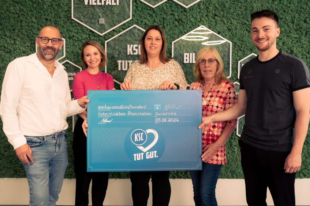 Fünf Personen halten einen großen symbolischen Scheck in der Hand. Der Betrag von 1.500 € wird an das Gabenlädchen in Rheinstetten übergeben.