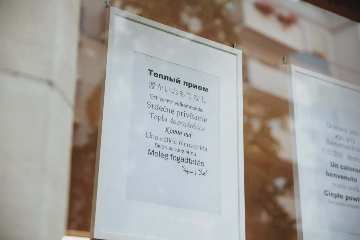 Im Schaufenster vom QUINO, Quartier Innenstadt Ost, hängt ein Blatt, auf dem in vielen verschiedenen Sprachen 