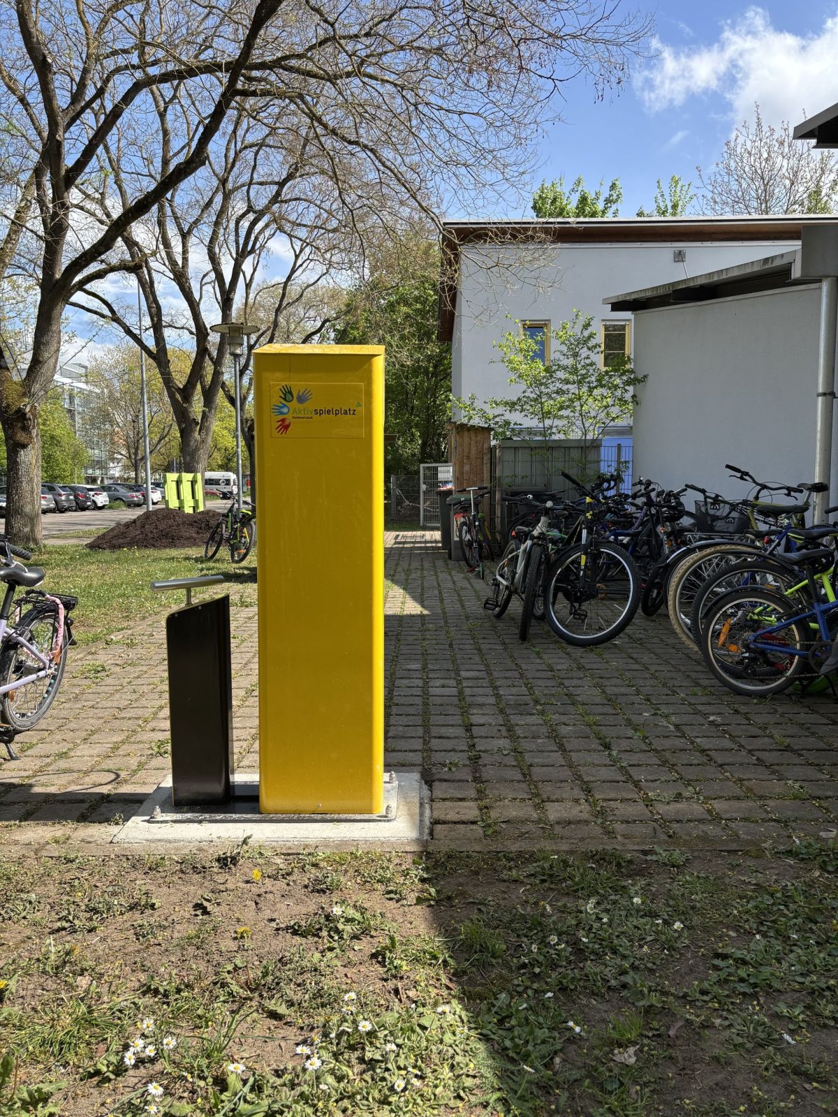 Vor dem Aktivspielplatz steht eine gelbe Fahrrad-Reparatursäule.