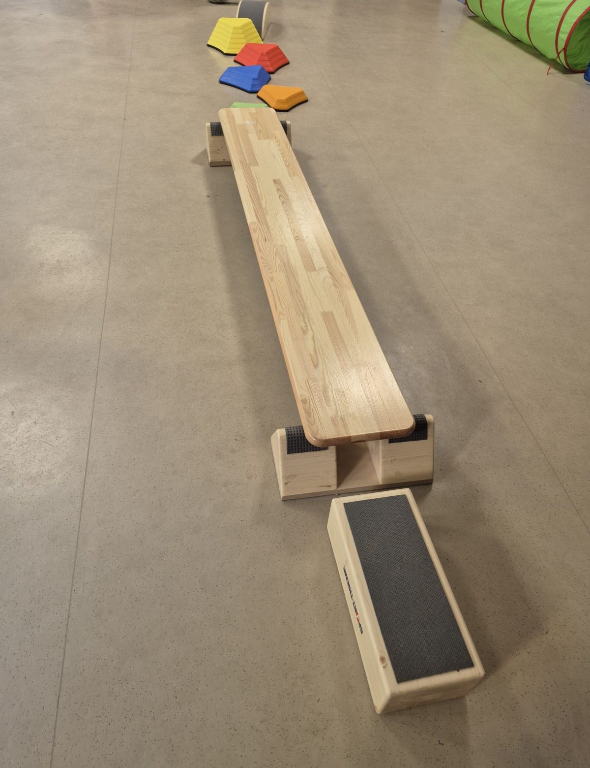 Aus einem Brett und Holzwürfeln wurde ein Bewegungsparcours für kleine Kinder aufgebaut.