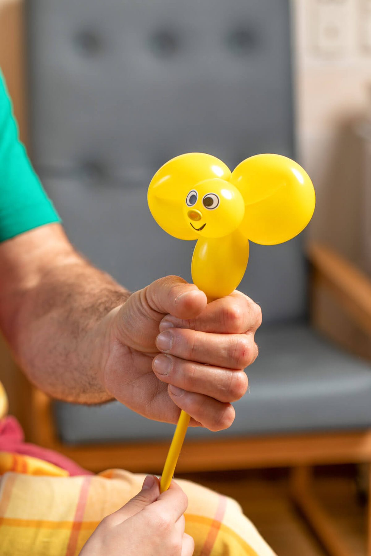 Ein Klinikclown hält eine Luftballon-Maus in der Hand.