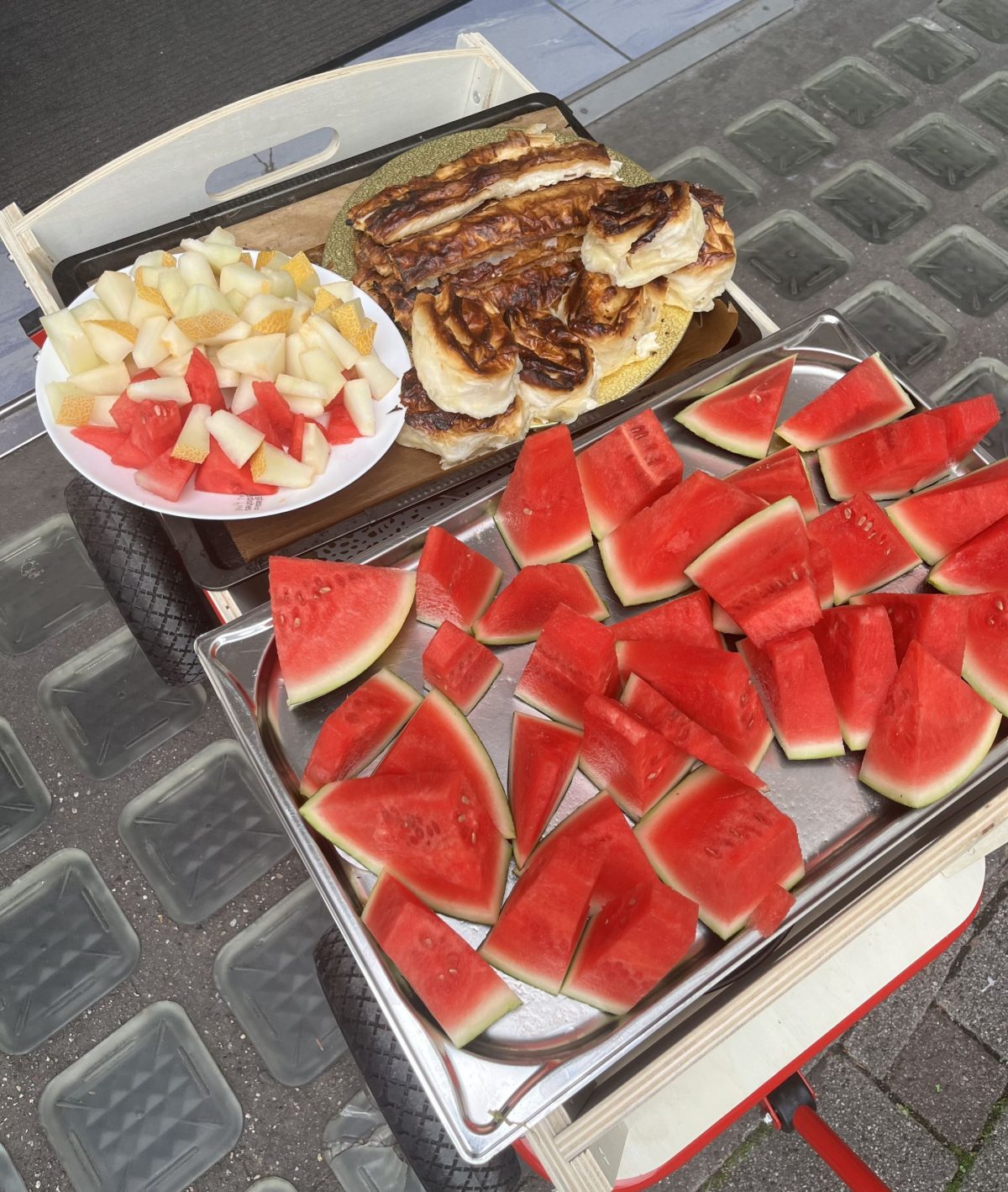 Auf einem Rollwagen steht ein Tablett mit Melonenstücken und anderem Fingerfood.
