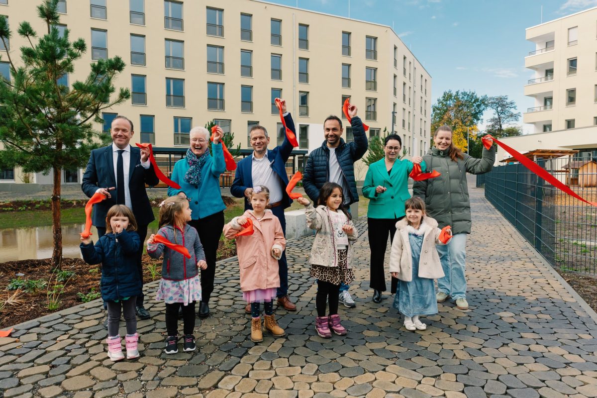 Eine Gruppe von Erwachsenen und Kindern steht und hält bunte Bänder in den Händen