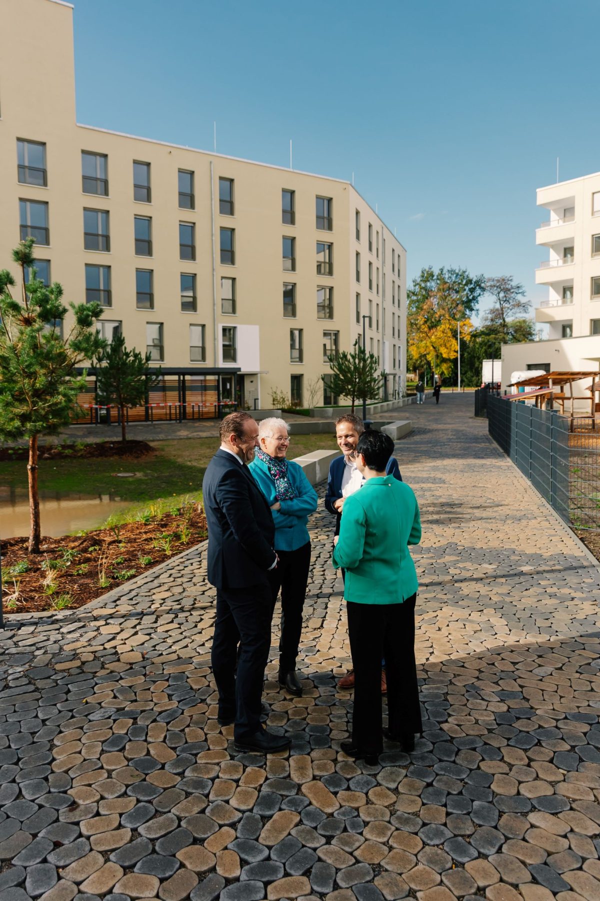 Daniel Fluhrer, Ellen Winkler, Stefan Storz und Annett Jura stehen im Kreis in der Sonne und unterhalten sich. Im Hintergrund ist das Gelände des August-Klingler-Areals zu sehen.