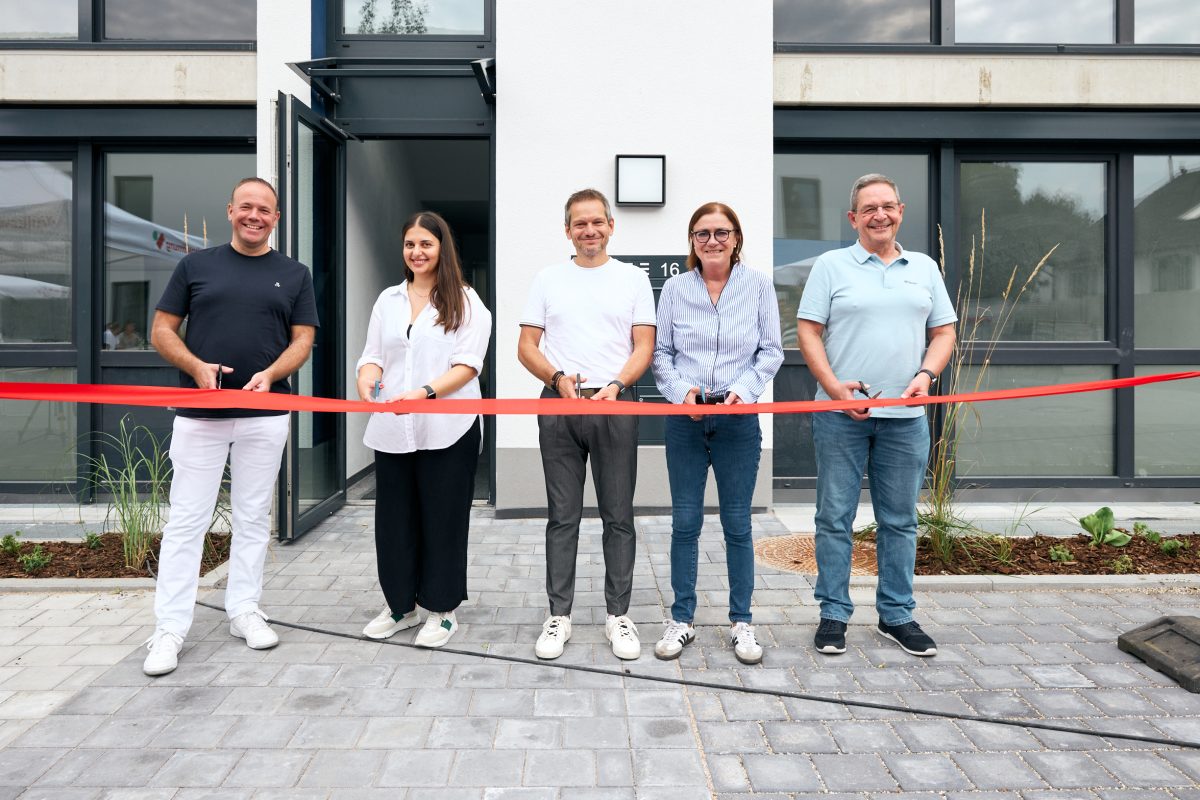 Fünf Personen stehen und halten gemeinsam ein rotes Band zur Eröffnung