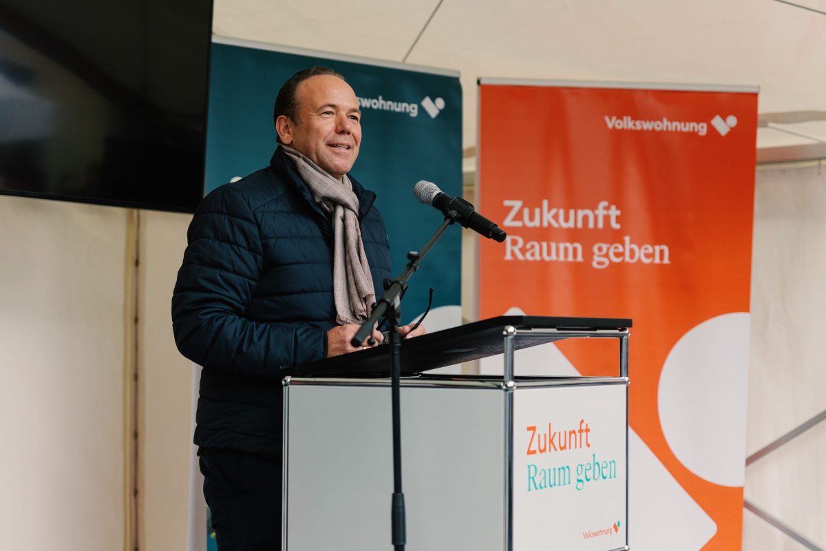 Baubürgermeister der Stadt Karlsruhe und Aufsichtsratsvorsitzender der Volkswohnung, Herr Daniel Fluhrer steht am Rednerpult und eröffnet die Fertigstellungsfeier des August-Klinger-Areals in Karlsruhe Daxlanden.