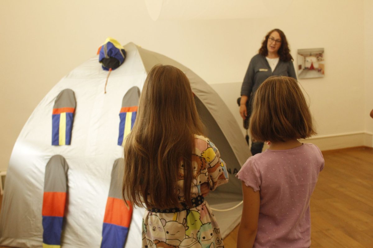 Zwei Kinder stehen vor einem Iglu-Zelt und hören einer Kunstpädagogin zu.