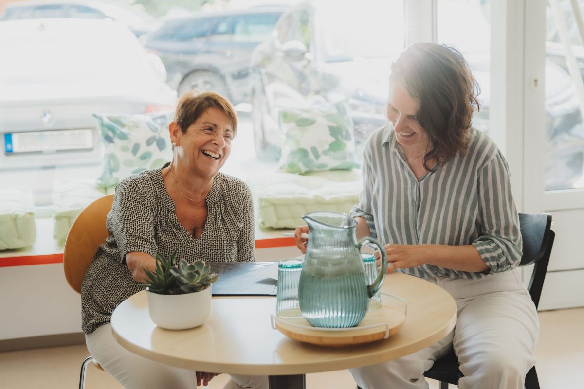 Zwei Frauen sitzen an einem Tisch im Quartiersbüro in Mühlburg und unterhalten sich.