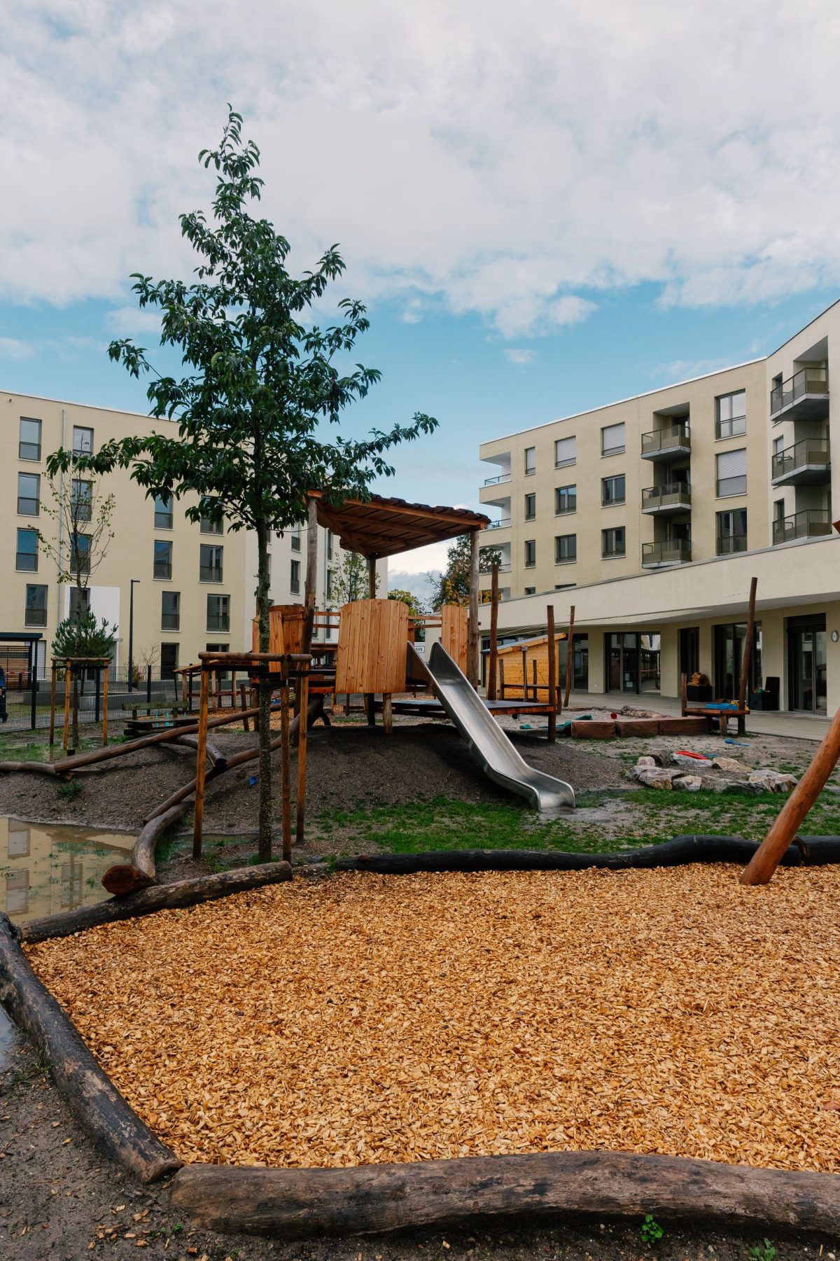 Ein Spielplatz mit verschiedenen Spielgeräten. Eine Rutsche steht in der Mitte des Bildes.