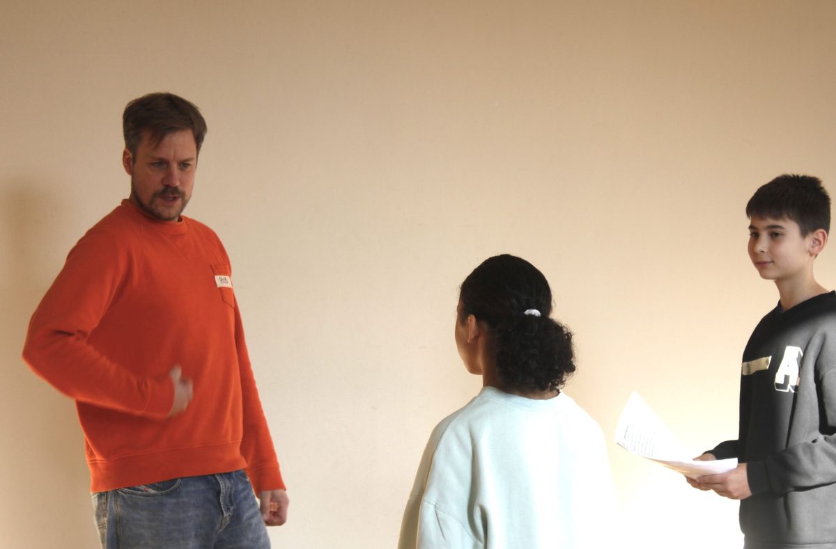 Ein Erwachsener übt mit zwei Kindern Posen für ein Theaterstück