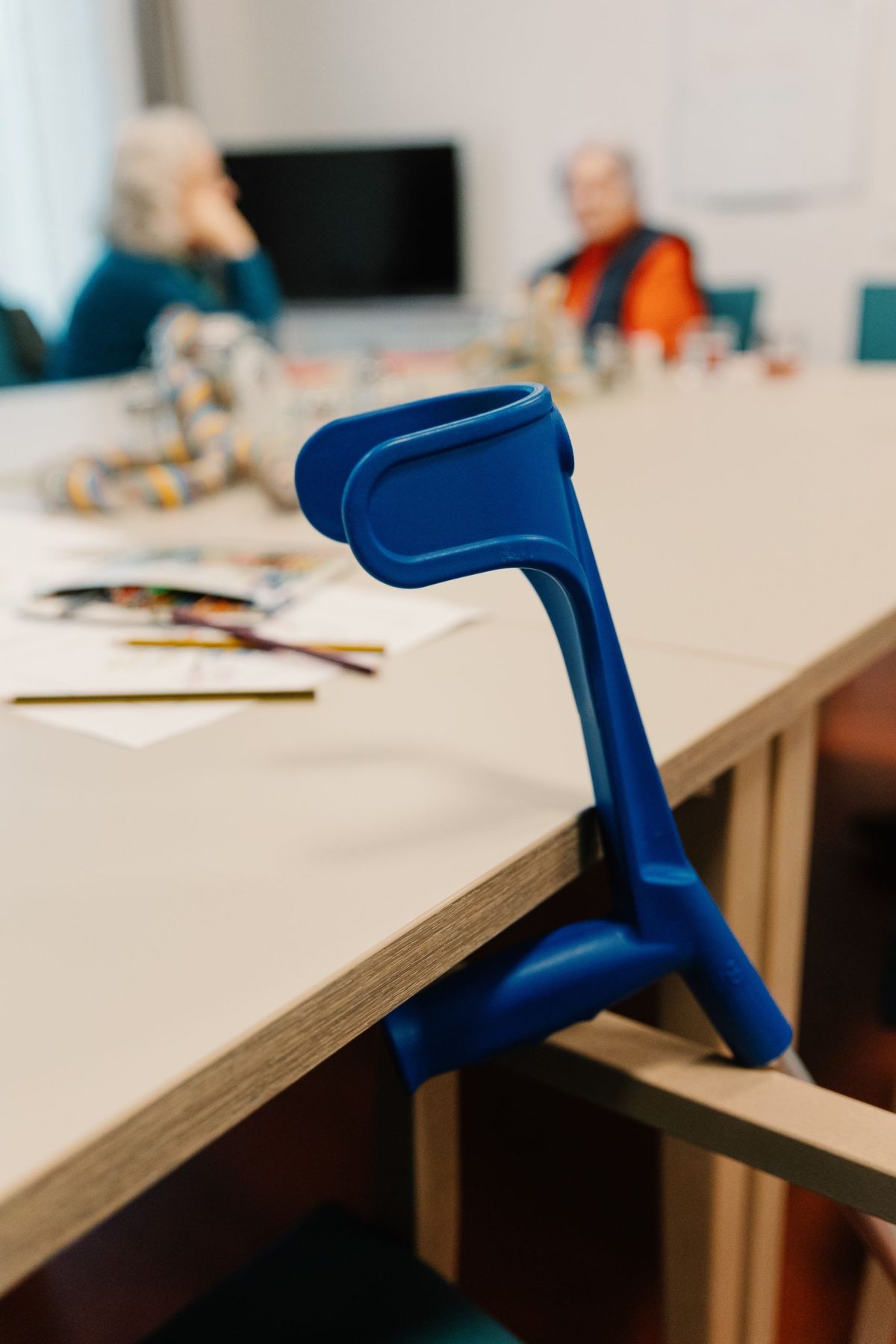 Eine blaue Gehhilfe, die am Tisch lehnt.