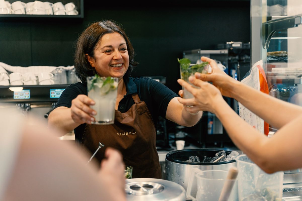 Die Leitung des Café Samocca-Augustine steht hinter der Bar und verteilt Limonaden an die Gäste.