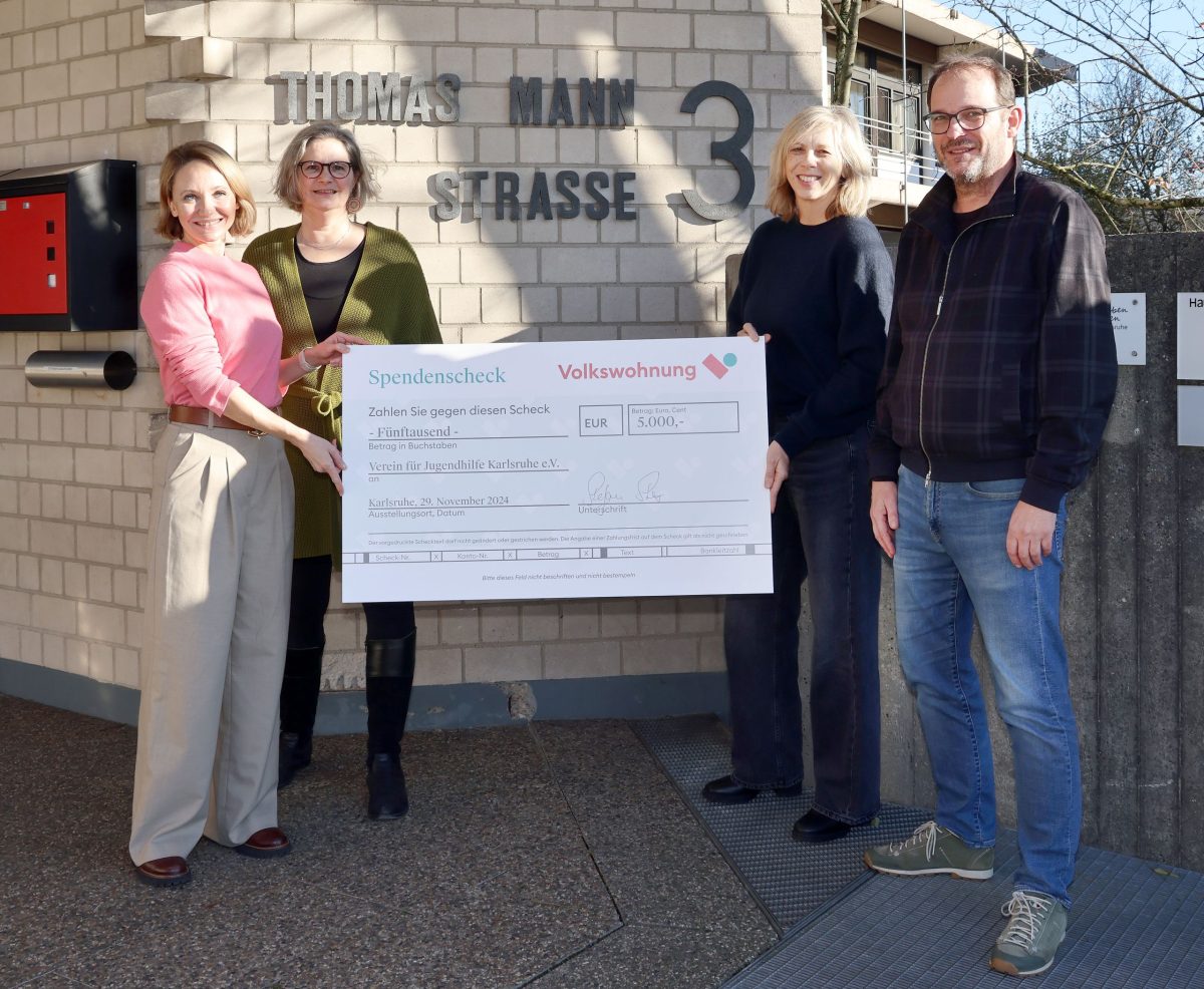 Weihnachtsspende an den Verein für Jugendhilfe. Vier Erwachsene stehen vor einem Gebäude, lächeln und halten einen großen Spendenscheck über 5.000 Euro in den Händen.