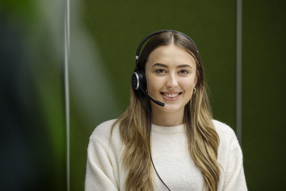 Eine lächelnde Frau, die ein Headset mit Mikrofon trägt.